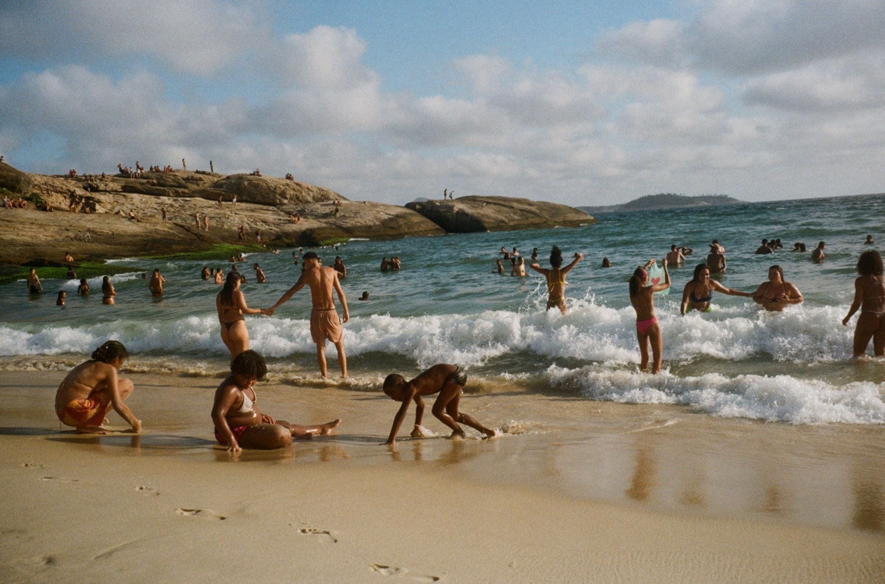 Bathers in the surf beside the rocks at Arpoador in the late afternoon