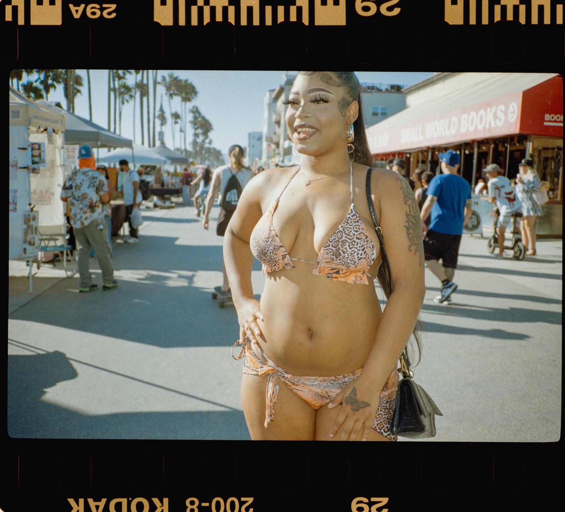 Woman in a leopard-print bikini smiling on the Venice boardwalk